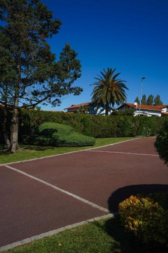 un court de tennis avec un palmier et un bâtiment dans l'établissement Chambre privée - Le Boudoir Tropical, à Hendaye