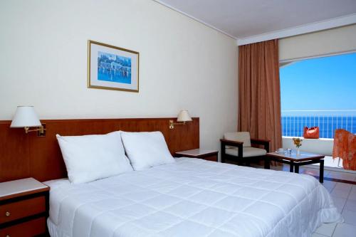 a hotel room with a bed and a large window at Sunshine Corfu Hotel And Spa in Nisakion
