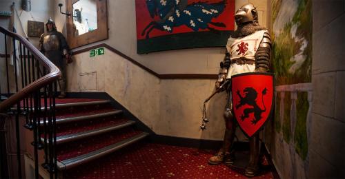 a statue of a man holding a surfboard in a hallway at Castle Rock Hostel - Adults Only in Edinburgh
