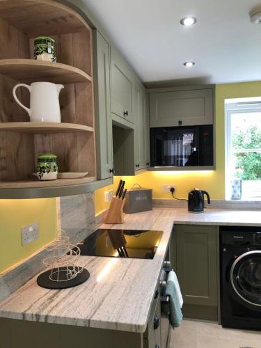a kitchen with green cabinets and a counter top at Little Grey Barn in Pagham