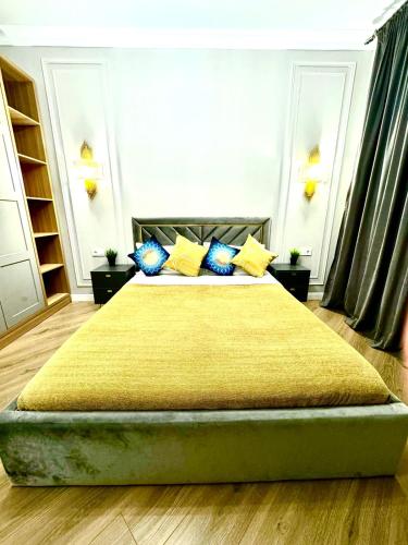 Un dormitorio con una cama grande con almohadas azules y amarillas. en ЖК METROPOLE Business, en Almaty