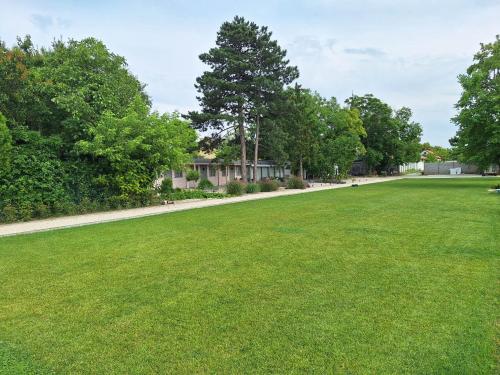 a large grass field with trees and a sidewalk at Zam-zam apartmanok in Zamárdi