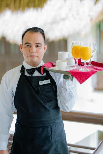 a man holding a tray with two glasses of orange juice at Daluyon Beach and Mountain Resort in Sabang