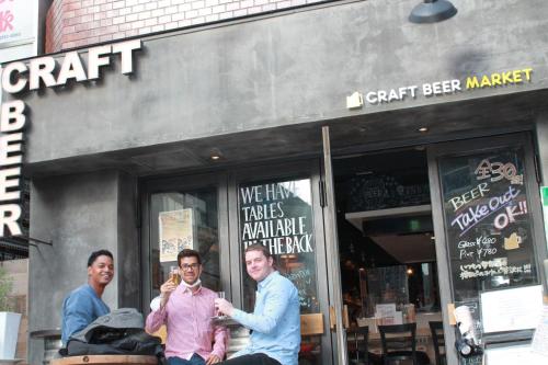a group of men sitting outside of a craft beer market at GrapeHouse Koenji in Tokyo