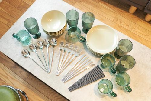 a table with plates and forks and glasses on a table at Frontier Comfort Kitaikebukuro by Tranova in Tokyo