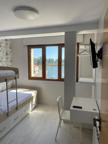 a bedroom with a bed and a desk and a window at Apartamento Serea in Villanueva de Arosa
