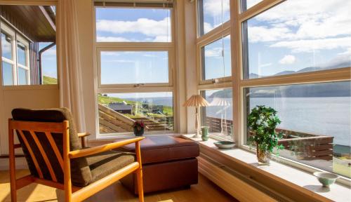 a room with a chair and a desk with windows at Sea & Mountain View 4 Bedroom in Leynar