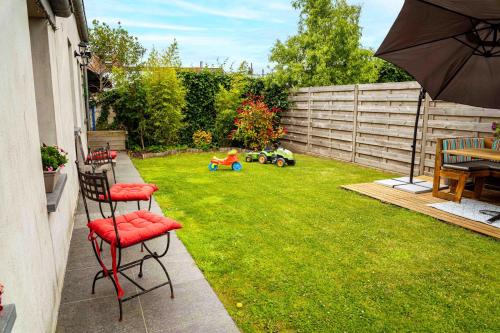 a backyard with a lawn with two chairs and an umbrella at Oase 't Huyseke in Blankenberge