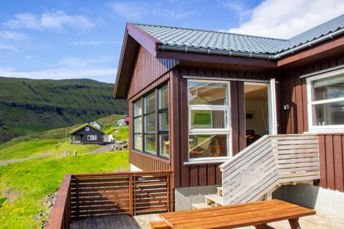 a wooden house with a bench on a deck at Sea & Mountain View 4 Bedroom in Leynar
