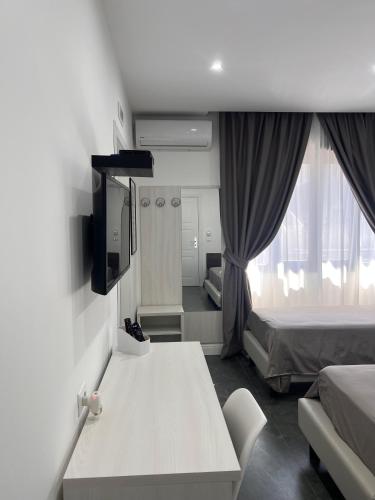 a room with a bed and a table and a tv at Hotel Blanc in Casoria