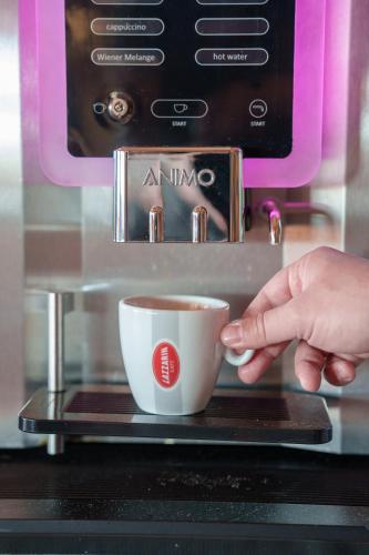 a person is reaching for a cup of coffee at Hotel Villa Strassoldo "Ex Attianese Hotel Restaurant" in Cervignano del Friuli