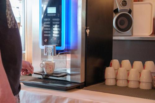 a person is making a coffee in a microwave at Hotel Villa Strassoldo "Ex Attianese Hotel Restaurant" in Cervignano del Friuli