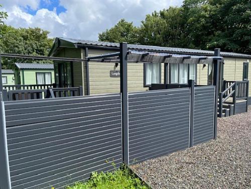 a wooden fence in front of a house at Lomond Woods Holiday Park in Balloch