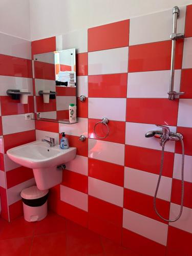 a red and white bathroom with a sink and shower at MEGA Apartments in Fushë-Draç