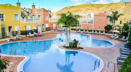 een groot zwembad met palmbomen en gebouwen bij Paraiso Ocean View in Palm-mar