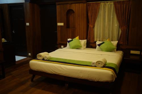 a bedroom with a large bed with green pillows at God's Own country Kovalam By Bestinn Leisure in Vilinjam