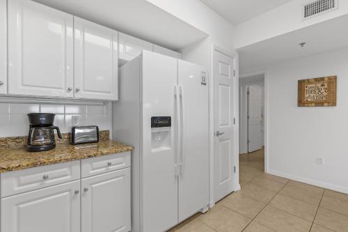 a kitchen with white cabinets and a white refrigerator at Oceanwalk 9-604 in New Smyrna Beach