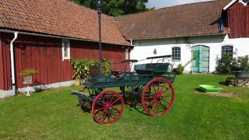 a green and red carriage in front of a barn at Lilla Trulla Gårdshotell - Feels like home in Bolestad