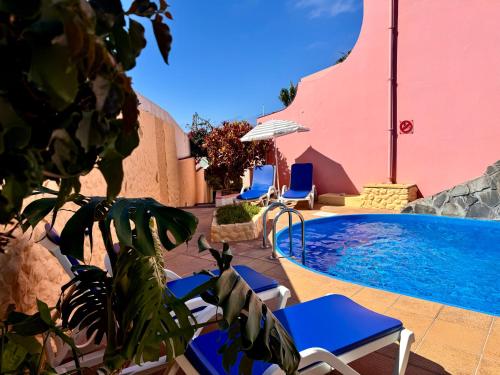 a pool at a hotel with chairs and a swimming pool at Falesia Gardens in Caniço