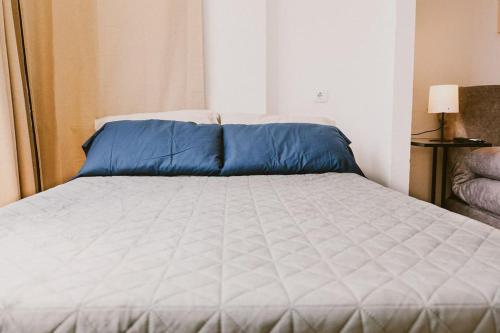 a bed with blue pillows on it in a room at Estudio en Torre del Mar a 3 minutos andando de la playa in Torre del Mar