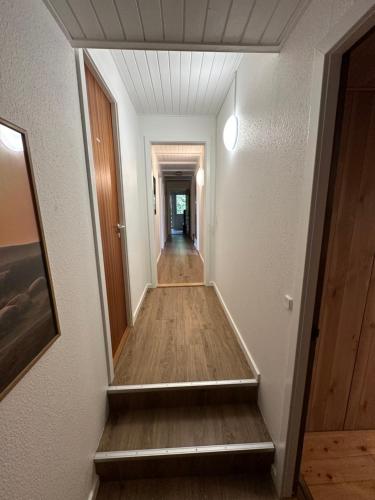 a hallway leading to a room with white walls and wood floors at Skovbrynet 2 The place for you in Løkken