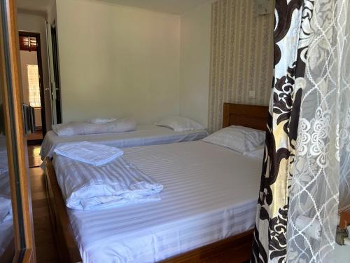 two beds in a room with white sheets at Pensiunea Hanzu Darius in Gura Rîului