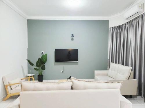 a living room with white furniture and a flat screen tv at IPOH MENGLEMBU LOHAS 4BR3Bath14 PAX in Ipoh