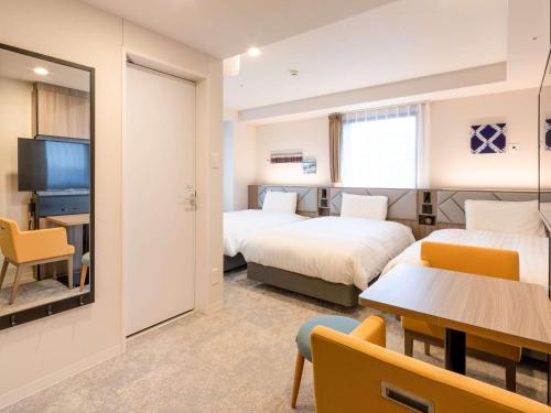 a hotel room with two beds and a table at Comfort Hotel Nagoya Kanayama in Nagoya