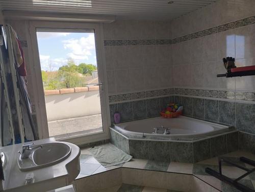 une salle de bain avec une baignoire, un lavabo et une fenêtre dans l'établissement Grande maison proche Nantes piscine chauffée couverte, à Vertou