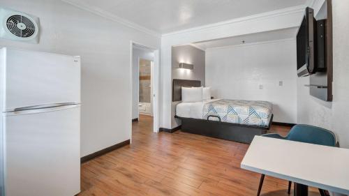a hotel room with a bed and a refrigerator at Studio 6 Ontario CA Convention Center Airport in Ontario