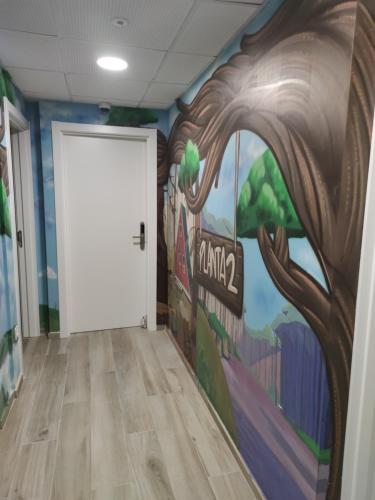 a hallway with a mural of a tree and a white door at FamilyHostelPinto in Pinto