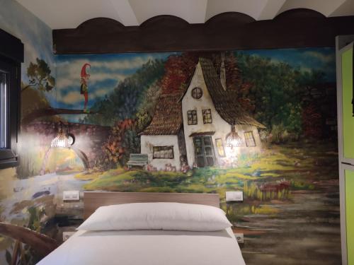 a bedroom with a painting of a house on the wall at FamilyHostelPinto in Pinto