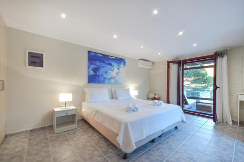 a bedroom with a large white bed and a window at KEOS by the sea in Korissia