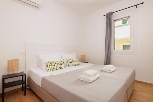 a white bedroom with a large bed with towels on it at Coastal Bliss Apartments in Glyfada