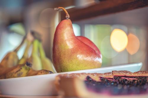 a plate with a pear and other fruits on a table at Logis Hôtel Restaurant Le Plantevin in Propiac