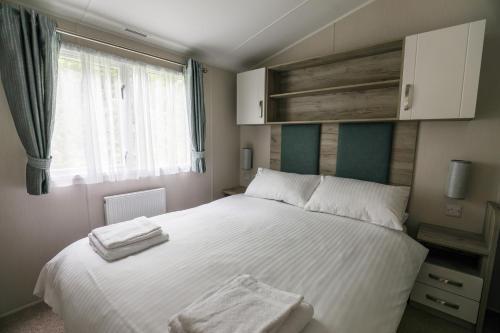 a bedroom with a white bed with towels on it at Tehidy Holiday Park in Illogan