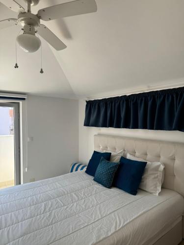 a bedroom with a white bed with blue pillows at Ocean Breeze guesthouse in Nazaré