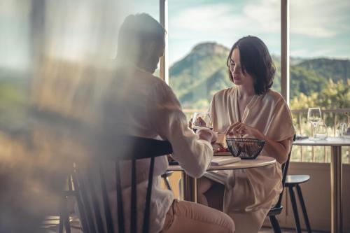 a man and a woman sitting at a table in a restaurant at Logis Hôtel Restaurant Le Plantevin in Propiac