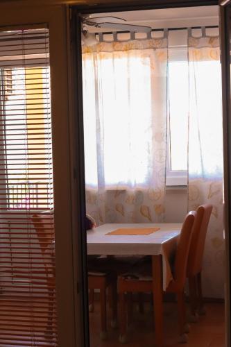a table and chairs in a room with windows at Apartments Panda in Bol