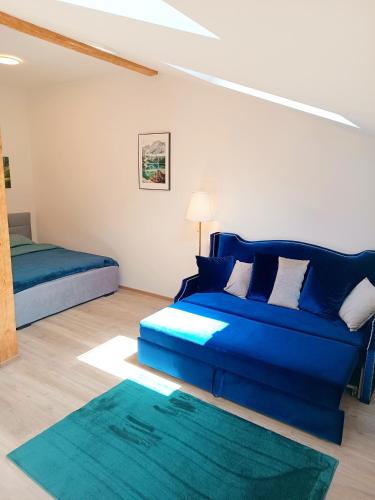 a living room with a blue couch and a bed at Apartments Romantic and Family Room Zemlinski in Payerbach