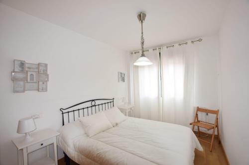 una camera da letto bianca con un letto e una sedia di Apartamento Alfredo a O Pindo