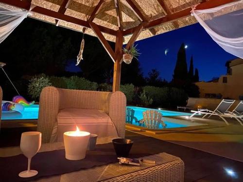 une bougie posée sur une table à côté d'une piscine la nuit dans l'établissement Villa, à Sorgues