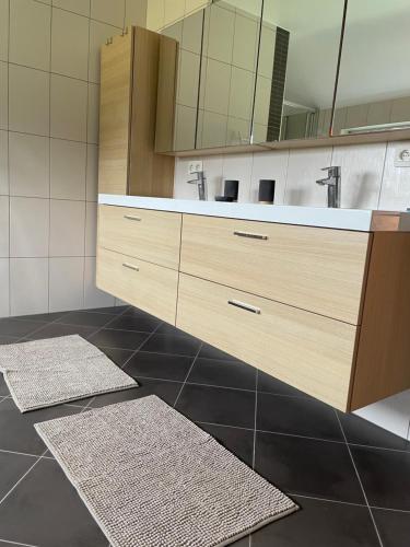 a bathroom with a vanity with a mirror and two rugs at Le Daguet in Florenville