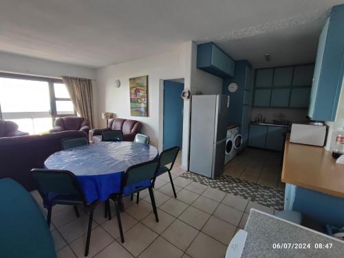 a living room with a table and chairs and a kitchen at Stella Maris 55 in Amanzimtoti