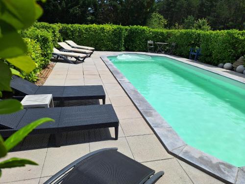 une piscine avec des chaises longues et une piscine dans l'établissement Villa les terre rouges avec piscine dans l ' Aude, à Arques