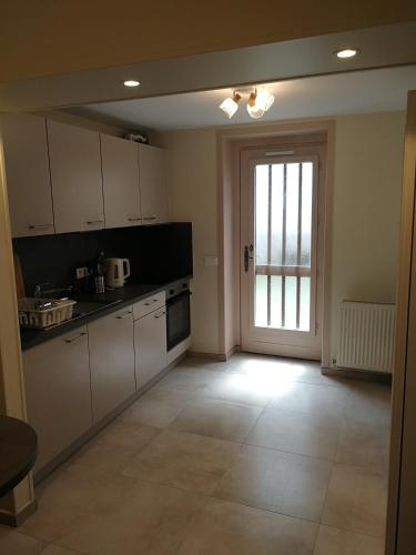 une cuisine avec des placards blancs et une grande fenêtre dans l'établissement Studio pour 3 personnes à 1 station de métro de Paris, à Saint-Denis