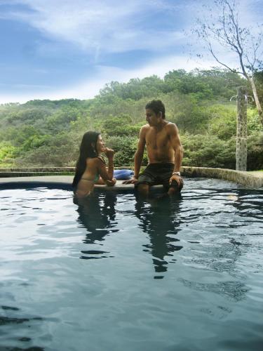 a man and a woman sitting in a swimming pool at Vida Aventura Ranch in Tanques