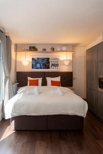 une chambre avec un grand lit blanc avec des oreillers orange dans l'établissement Marais, Rue Beaubourg - 6 places, à Paris
