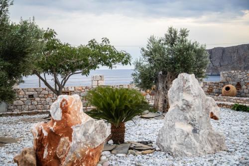 a garden with two large rocks and trees at Armenopetra View Gerolimenas in Gerolimenas