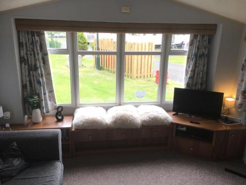 a living room with a couch and a large window at Beautiful 3 bed caravan SouthviewPark Skegness in Skegness